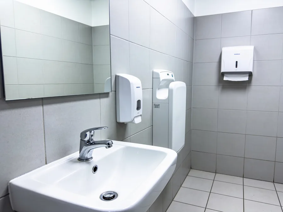 Rengjort toilet med håndvask og dispensere på tankstation
