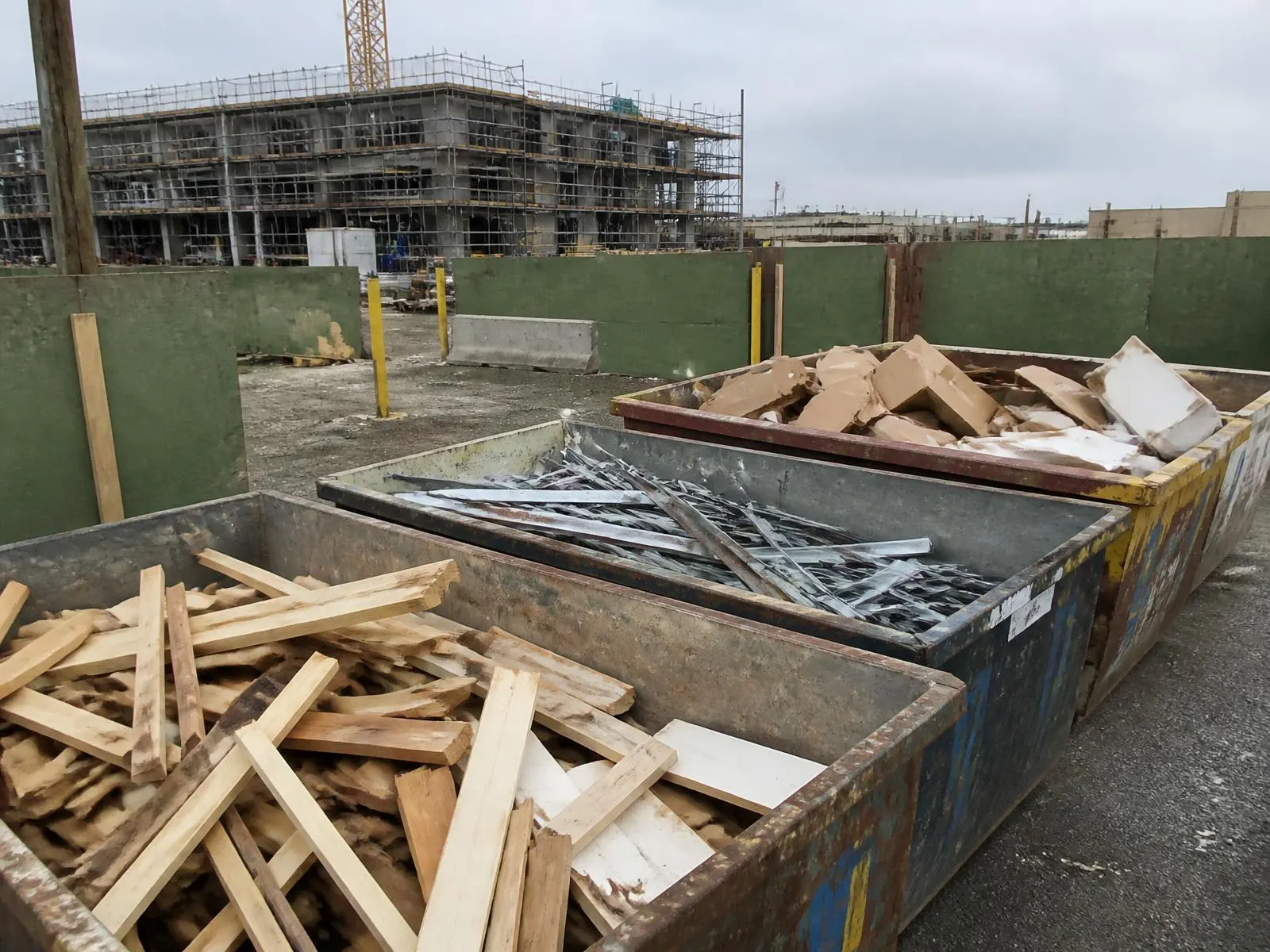 Containerplads med sorteret træ, metal og pap på byggeplads